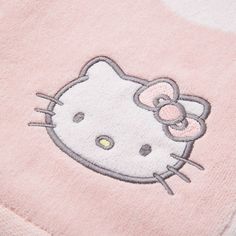 a close up of a hello kitty towel on a white surface with a pink background