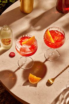 three different types of cocktails on a table with bottles and spoons next to them