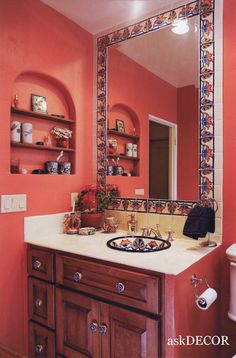 a bathroom sink sitting under a mirror next to a shelf filled with vases and other items