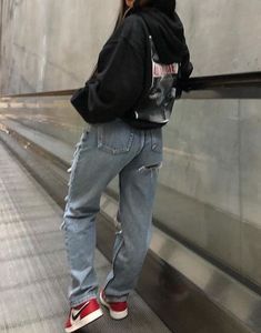 a woman standing on an escalator with her back to the camera and looking down