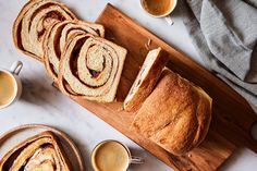 slices of cinnamon swirl bread on a cutting board with cups of coffee next to it