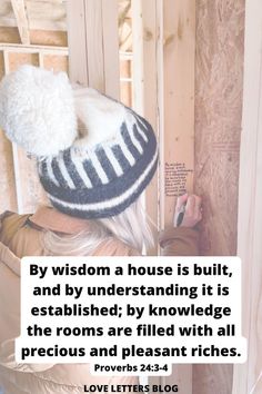 a woman wearing a hat and writing on the side of a wooden wall with a quote above it