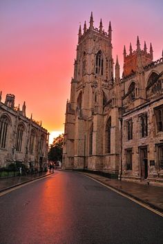 the sun is setting in front of an old building with tall towers and spires