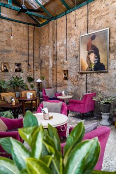 a living room filled with lots of furniture next to a wall covered in pictures and plants