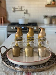 three bottles of gold paint sitting on top of a white plate in front of a kitchen counter