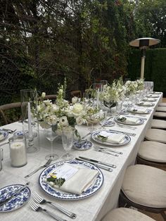 a long table with plates and silverware is set for an outdoor dinner party in the garden