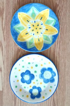 two plates sitting on top of a wooden table next to each other with flowers painted on them