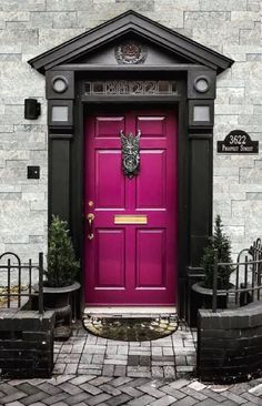 a purple door is in front of a white brick building