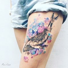 a woman's thigh with flowers and a bird on it, painted in watercolor