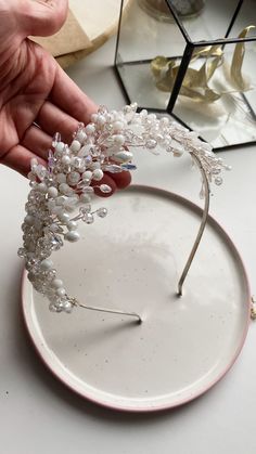 a person is holding a tiara with pearls on it