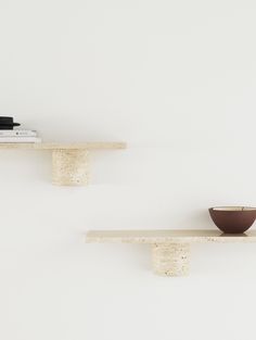 two shelves with bowls on them against a white wall, one shelf has a book and the other is a bowl