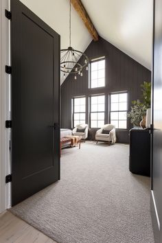 an open door leading to a living room with two couches and a chandelier