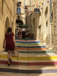 a woman in a red dress is walking down some stairs