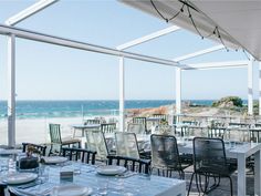 an outdoor dining area with tables and chairs overlooking the ocean