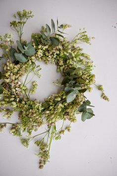 a wreath made out of flowers and greenery on a white surface with space for text