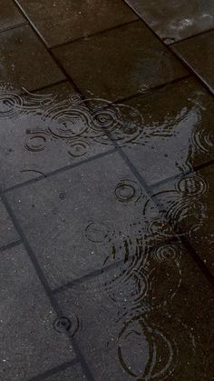 an umbrella is reflected in the puddles of water on the sidewalk, with another umbrella nearby