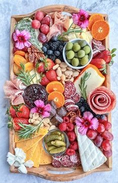 a platter filled with fruits, nuts and cheeses on top of a marble counter