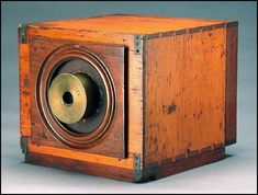 an old wooden box with a brass bell on the front and side, sitting on a gray background