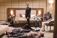 a group of people in suits and ties laying on the floor next to a bed