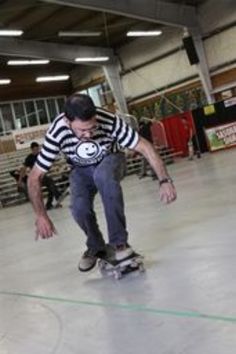 a man riding a skateboard on top of a hard surface covered floor in a warehouse