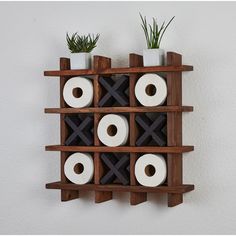 two wooden shelves with rolls of toilet paper and plants in them on top of each shelf