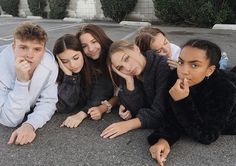 a group of young people laying on the ground in a parking lot with their mouths open