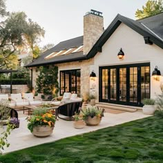 an outdoor patio with potted plants and seating area next to the house at dusk