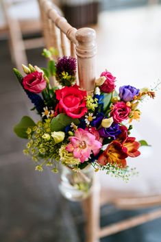 a vase filled with colorful flowers on top of a wooden chair