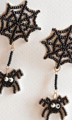 two black and white beaded earrings with an evil spider hanging from it's side