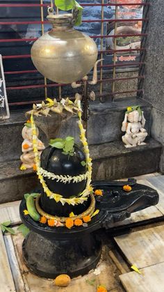 there is a black vase with flowers on it and an orange garland around the neck