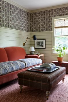 a living room with a couch, ottoman and coffee table in front of a window