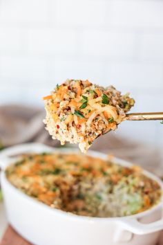 a close up of a spoon full of food with broccoli in the background