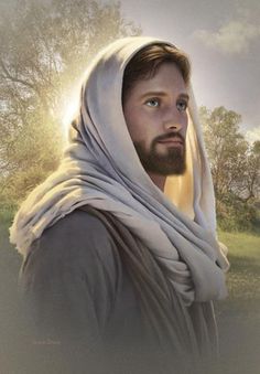 a man with a beard wearing a white shawl and looking at the camera while standing in a field