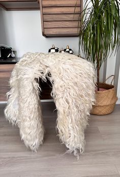 a large white furry chair sitting next to a potted plant