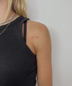 a woman wearing a black tank top with a small tattoo on her left arm and neck