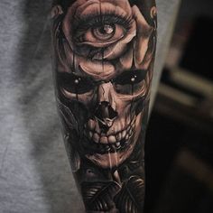 a man's arm with a skull and rose tattoo design on the left forearm