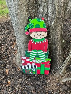 a wooden sign with a christmas elf sitting in front of a tree