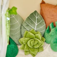 green and brown pillows are sitting on a bed next to a pillow with a leaf design