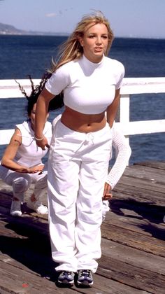 a woman in white is standing on a dock