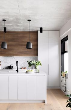 a modern kitchen with white cabinets and wood accents on the countertops, along with potted plants