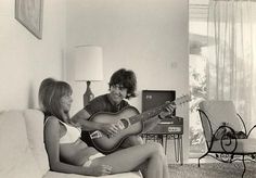 two people sitting on a couch playing guitar