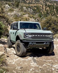 a green truck is driving down a rocky trail