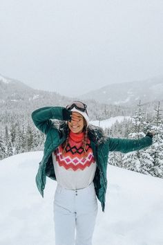 a woman standing on top of a snow covered slope