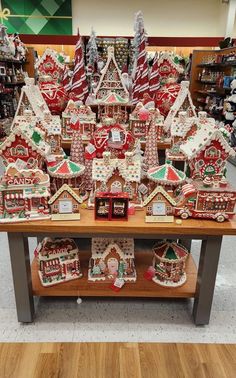 a table covered in gingerbread houses and other christmas decorations on display at a store