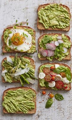 four slices of bread with avocado, tomato, lettuce and an egg on top