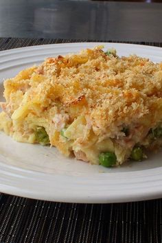 a white plate topped with a casserole covered in meat and veggies