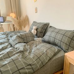 a bed with two pillows on it and a stuffed animal sitting on the pillow next to it