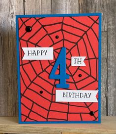 a red and blue birthday card with the number four on it's side, in front of a wooden background