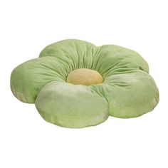 a green flower shaped pillow sitting on top of a white surface with a light yellow center