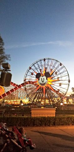 an amusement park with a ferris wheel and mickey mouse on it's face at night